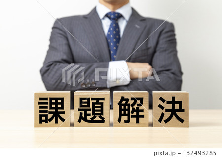 「課題解決」と書かれたブロックと腕組みをするビジネスマン 132493285