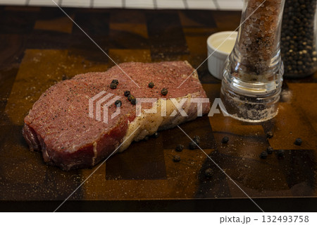 Fresh Raw Beef Steak With Rub On The Wood Board, A fresh raw beef steak with spice rub lies on a wood board, bold flavors shining, great for a gourmet photo session or a hearty meal exhibit. 132493758