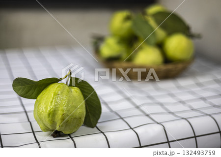 Green Guava In The Bamboo Basket On The Table, Fresh green guavas fill a bamboo basket on the table, their crisp texture gleaming under soft light, perfect for a food photo or tropical fruit. Green Guava In The Bamboo Basket On The Table, Fresh green guavas fill a bamboo basket on the table, their crisp texture gleaming under soft light, perfect for a food photo or tropical fruit. 132493759