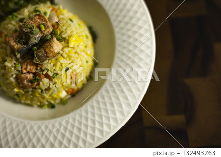 Plate Of Salmon Fried Rice On Rustic Wooden Table, A savory plate of salmon fried rice sits on a rustic wooden table, steam rising with vibrant grains, perfect for a food photo or hearty meal. 132493763
