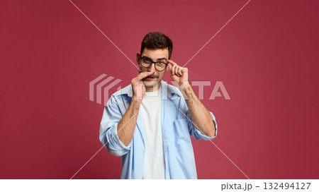 Curious man adjusting glasses with attentive look showing interest and focus 132494127