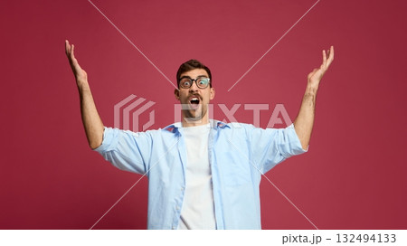 Excited man raising hands with joyful open mouth expressing surprise and happiness Excited man raising hands with joyful open mouth expressing surprise and happiness 132494133