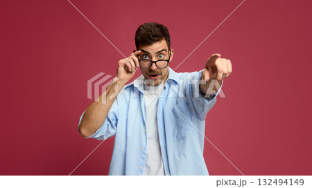 Surprised man pointing finger forward with amused facial expression 132494149