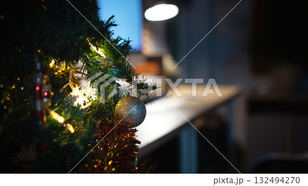 Close-up Christmas tree with glowing lights beside cozy home office at night 132494270