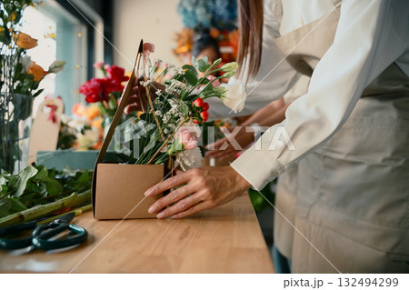 Closeup people learning to arrange flowers in a creative workshop, crafting colorful bouquets with teamwork Closeup people learning to arrange flowers in a creative workshop, crafting colorful bouquets with teamwork 132494299