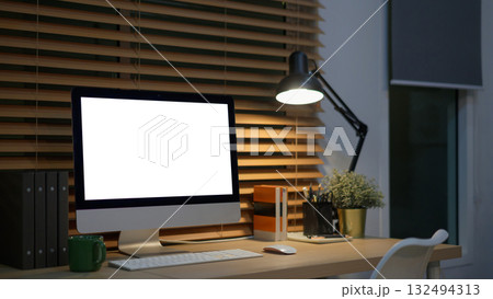 Computer on desk in peaceful nighttime workspace with office supplies 132494313