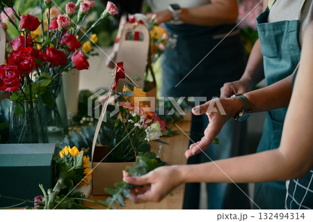 Closeup people learning to arrange flowers in a creative workshop, crafting colorful bouquets with teamwork Closeup people learning to arrange flowers in a creative workshop, crafting colorful bouquets with teamwork 132494314