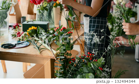 Focus on Hypericum branches and fresh flowers arranged during a creative floral workshop 132494344
