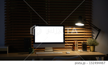 Warm nighttime workspace with computer and soft desk light Warm nighttime workspace with computer and soft desk light 132494467
