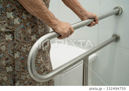 Asian elderly woman patient use handrail safety in toilet support rail in bathroom. 132494750