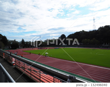 緑のフィールドと青空の下で競技が行われる陸上競技場 緑のフィールドと青空の下で競技が行われる陸上競技場 132496040
