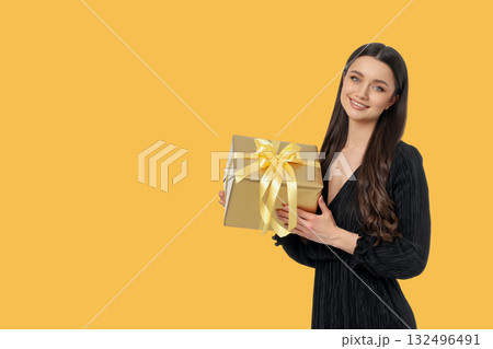 Woman presents a gold gift box with a yellow ribbon 132496491