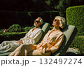 A man and a woman are sitting on a lawn chair, both wearing sunglasses 132497274