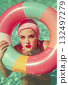 A woman in a bikini is holding a pink and yellow inflatable ring in a pool 132497279