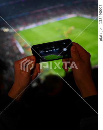 Person is holding a cell phone and taking a picture of a soccer field 132498008