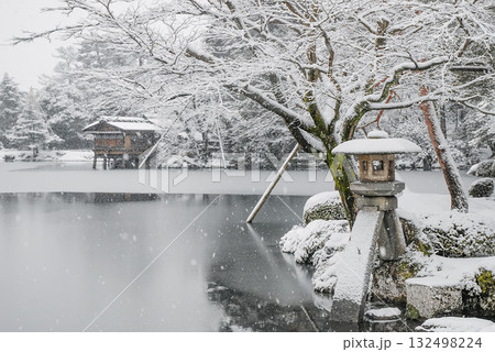 金沢・兼六園の雪景色、霞ヶ池のほとりに佇む徽軫灯籠と雪に霞む内橋亭の冬景 132498224