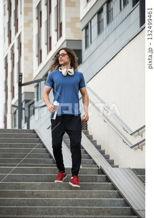 Sporty man and athlete wearing blue t-shirt running at stair in modern city. Cardio workout training. Back view. Healthy lifestyle. Wellness 132499461