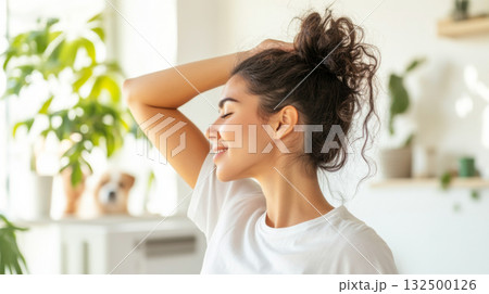 Young woman relaxing on sofa in bright living room surrounded by plants 132500126