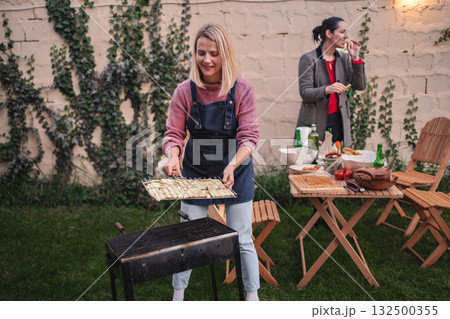 Enjoying a colorful evening barbecue with friends in a charming garden Enjoying a colorful evening barbecue with friends in a charming garden 132500355