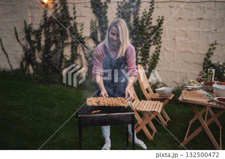 Grilling delicious skewers in a cozy outdoor backyard setting at dusk Grilling delicious skewers in a cozy outdoor backyard setting at dusk 132500472
