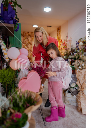 Mother and daughter explore a charming flower shop filled with vibrant blooms and heart-shaped decorations 132500719