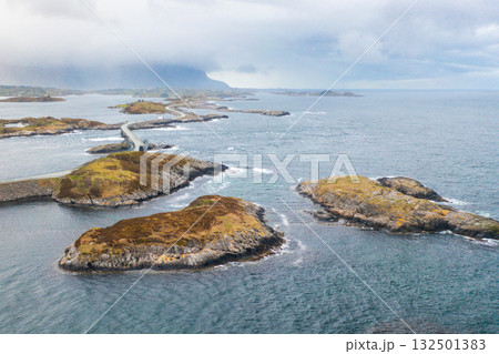 Curving bridges of the Atlantic Ocean Road stretch across small rocky islands, connecting Norways dramatic coastal landscape under cloudy skies. Curving bridges of the Atlantic Ocean Road stretch across small rocky islands, connecting Norways dramatic coastal landscape under cloudy skies. 132501383