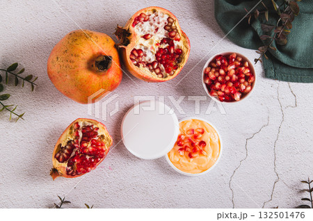 Pomegranate skin care cream in a jar and fruit on the table top view 132501476