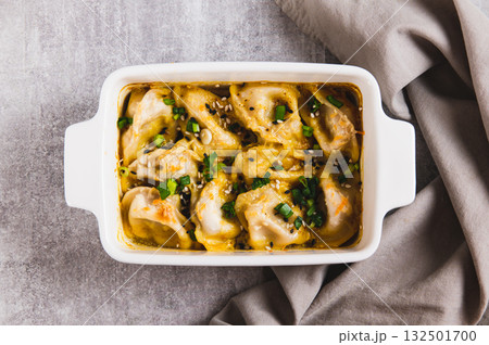 Close up of One-Pan Baked Dumplings with Herbs and Sauce in a Pan on the Table top view Close up of One-Pan Baked Dumplings with Herbs and Sauce in a Pan on the Table top view 132501700