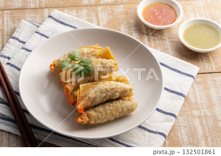 Deep Fried Crispy Wonton wrapped with shrimp and minced pork in white plate.Thai appetizer food with Sweet Chili Sauce and seafood sauce. 132501861