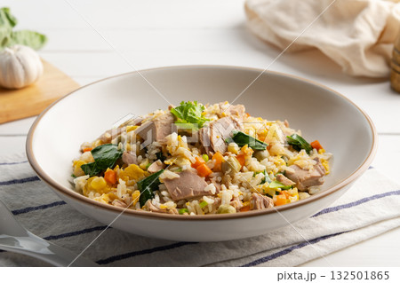 Tuna fried rice,stir fry rice with canned tuna fish ,kale ,corn ,carrot ,green peas and egg in white plate. 132501865