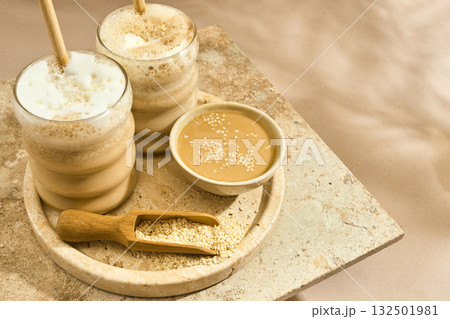 Sesame Tahini Latte Delight. Creamy sesame paste and iced tahini lattes on rustic travertine surface. Sesame Tahini Latte Delight. Creamy sesame paste and iced tahini lattes on rustic travertine surface. 132501981