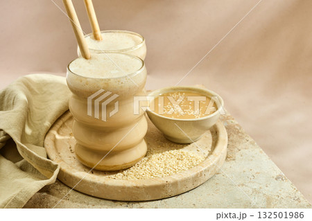 Sesame Tahini Latte Delight. Creamy sesame paste and iced tahini lattes on rustic travertine surface. Sesame Tahini Latte Delight. Creamy sesame paste and iced tahini lattes on rustic travertine surface. 132501986