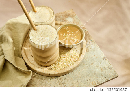 Sesame Tahini Latte Delight. Creamy sesame paste and iced tahini lattes on rustic travertine surface. Sesame Tahini Latte Delight. Creamy sesame paste and iced tahini lattes on rustic travertine surface. 132501987
