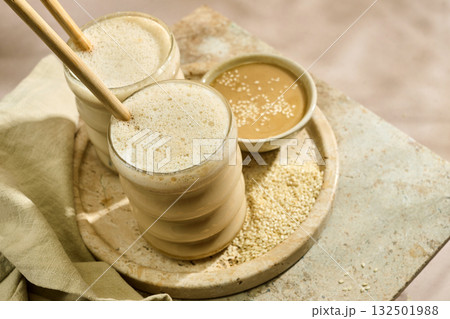 Sesame Tahini Latte Delight. Creamy sesame paste and iced tahini lattes on rustic travertine surface. 132501988
