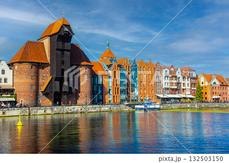 Scenic view of the historic waterfront in Gdansk, showcasing colorful buildings and the medieval crane along the Motlawa River, with vibrant activity from boats and pedestrians Scenic view of the historic waterfront in Gdansk, showcasing colorful buildings and the medieval crane along the Motlawa River, with vibrant activity from boats and pedestrians 132503150