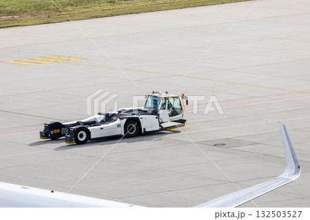 Modern regional jet aircraft towed by ground vehicle on airport taxiway tarmac under sunlight. Engine cockpit clearly visible crew performs technical operations before next scheduled flight airport Modern regional jet aircraft towed by ground vehicle on airport taxiway tarmac under sunlight. Engine cockpit clearly visible crew performs technical operations before next scheduled flight airport 132503527
