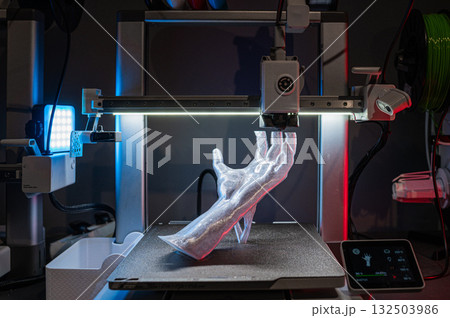 A 3D Printed Hand emerges from a printer, showcasing advanced craftsmanship and innovation A 3D Printed Hand emerges from a printer, showcasing advanced craftsmanship and innovation 132503986