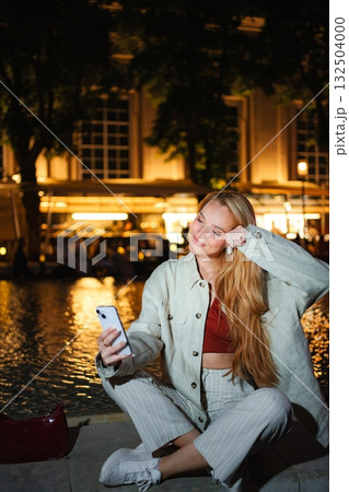 Young woman taking selfie with phone in Vienna at night Young woman taking selfie with phone in Vienna at night 132504000
