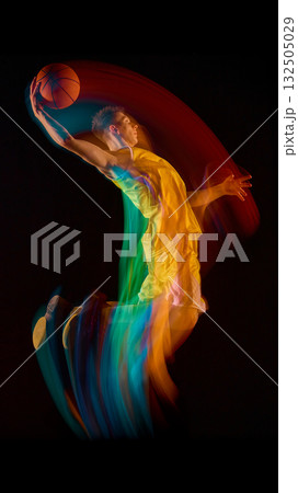 Basketball player in yellow uniform making dynamic jump with colorful motion trail 132505029