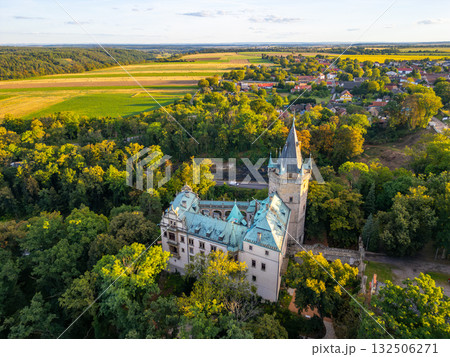 Stranov Castle stands proudly in Central Bohemia, surrounded by lush greenery and open fields. This aerial view captures the castle's unique architecture and scenic landscape during a sunny day. Stranov Castle stands proudly in Central Bohemia, surrounded by lush greenery and open fields. This aerial view captures the castle's unique architecture and scenic landscape during a sunny day. 132506271