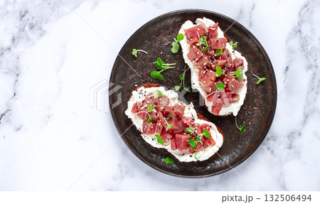 sandwiches, rye bread with cream cheese, sliced tuna fillet with herbs, breakfast on a black plate, homemade, 132506494