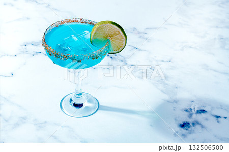 Bright blue cocktail with a slice of lime on a marble surface, 132506500