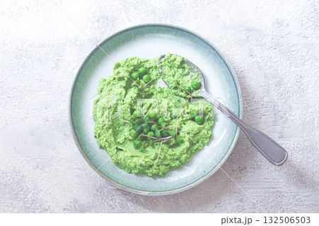Delicious green pea puree served in a stylish bowl garnished with fresh peas and microgreens for a healthy meal 132506503