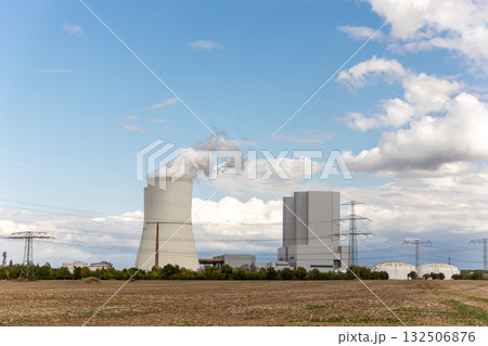 Massive cooling tower power plant Saxony  Germany releasing steam  cloudy sky. Industrial complex surrounded by fields illustrates modern energy generation, infrastructure environmental technology 132506876