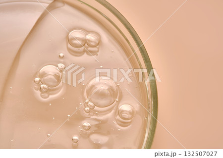 The texture of the serum in a petri dish on a beige background. The texture of the serum in a petri dish on a beige background. 132507027