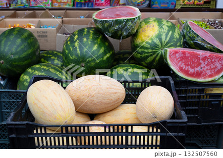 Melons and watermelons in outdoor market stall and juicy red watermelon cut in half. 132507560