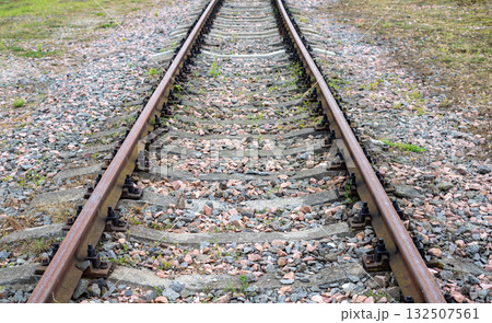 Perspective view of an empty, straight railway line disappearing into the horizon on a cloudy autumn day. Perspective view of an empty, straight railway line disappearing into the horizon on a cloudy autumn day. 132507561