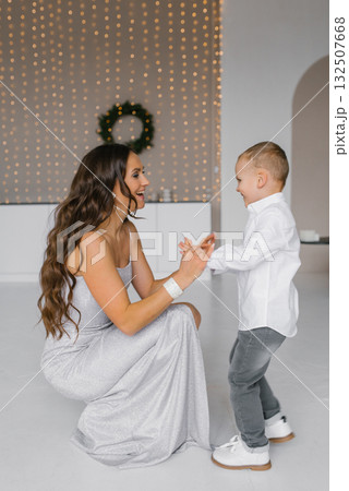 Happy mom and son are playing together in room with Christmas decorations Happy mom and son are playing together in room with Christmas decorations 132507668