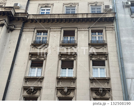 Historic stone building facade with sculpted ornaments and windows. Classical architecture, European heritage, and urban elegance in city center. Historic stone building facade with sculpted ornaments and windows. Classical architecture, European heritage, and urban elegance in city center. 132508190
