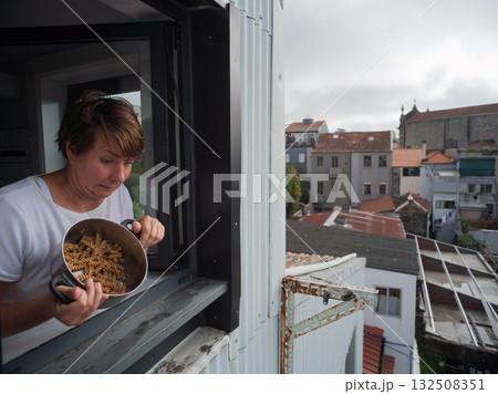 Woman throwing old spoiled pasta out of the window, bad neighbor conflict concept Woman throwing old spoiled pasta out of the window, bad neighbor conflict concept 132508351